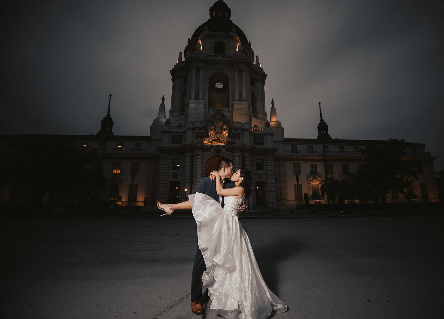 Pasadena City Hall lit at night with the bride’s dress turning in the courtyard below the dome