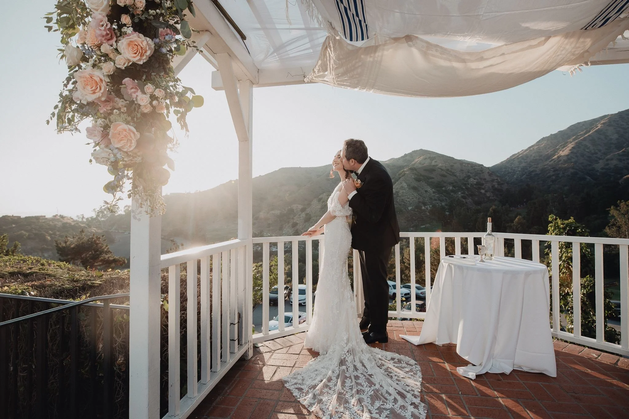 Couple kissing on the hilltop terrace at Castaway Burbank with the Verdugo hills behind them