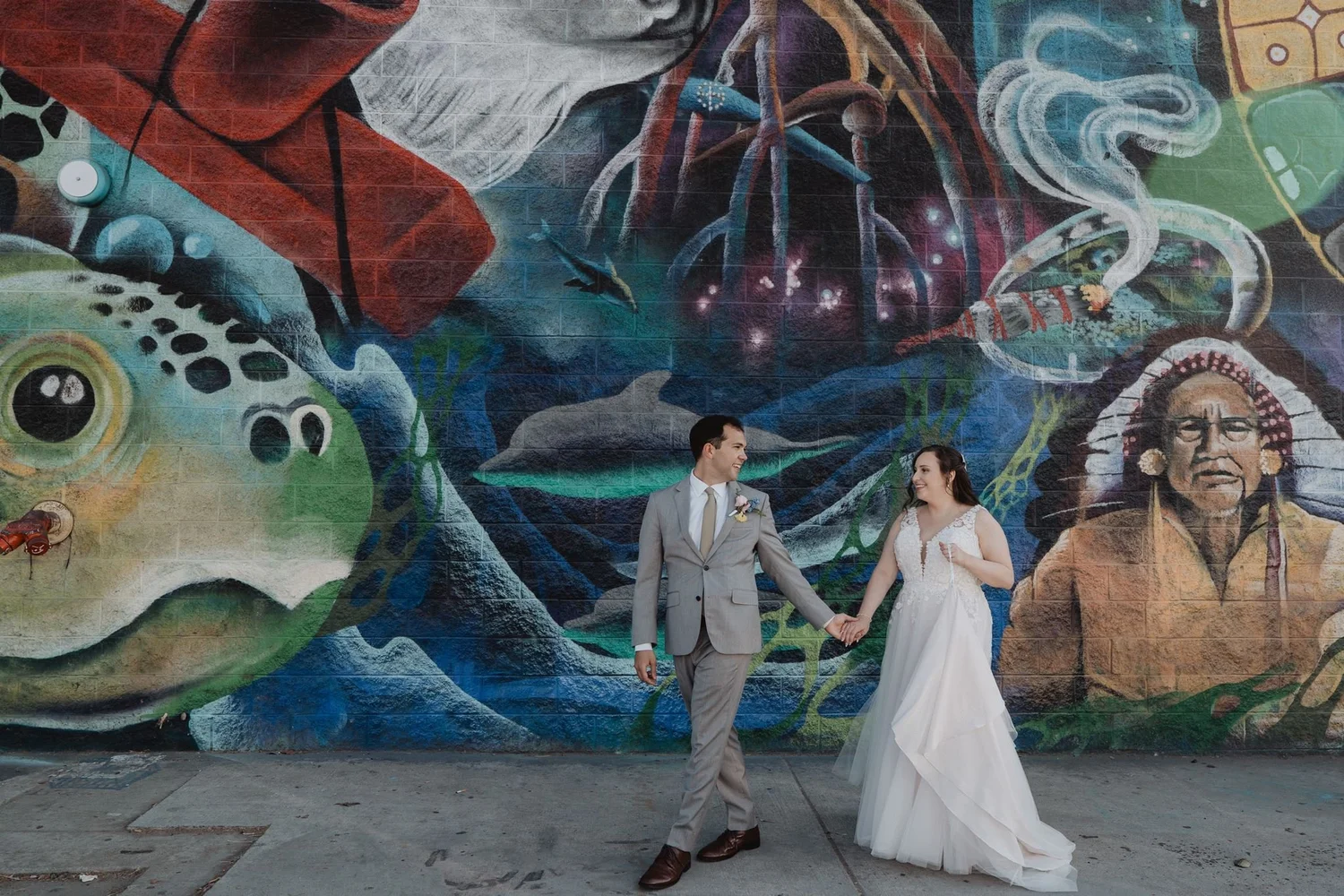 Couple walking past a large colorful street mural in the Arts District near Millwick