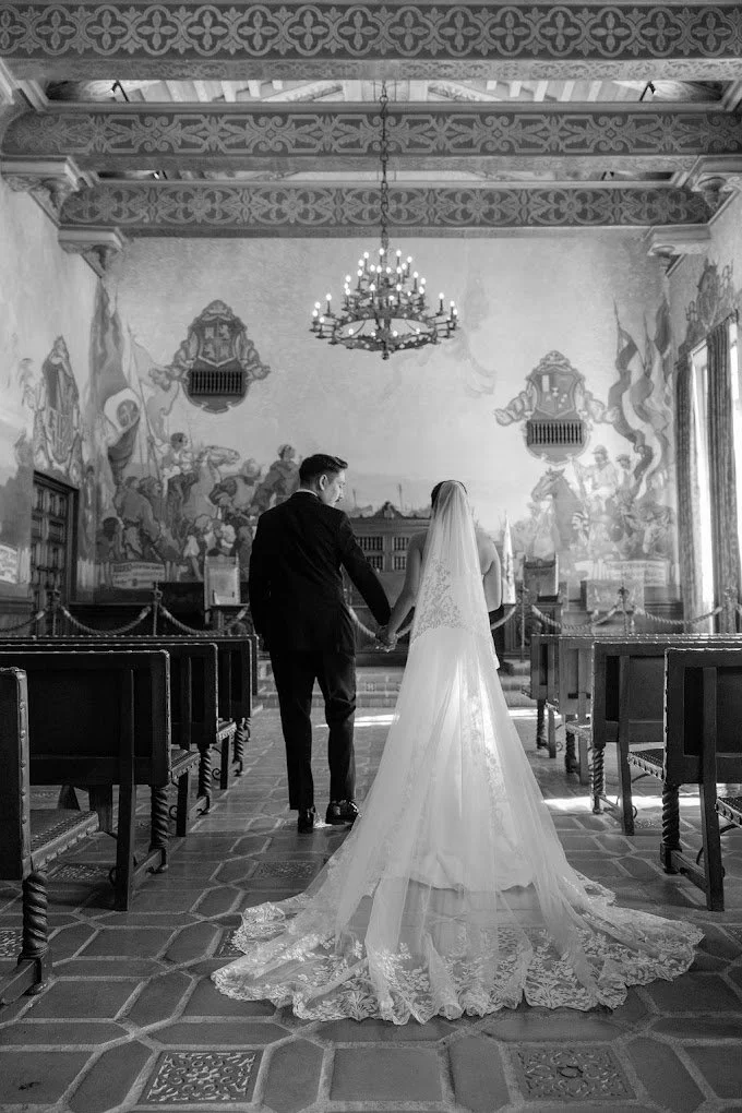 Black and white frame of the bride walking the chapel aisle