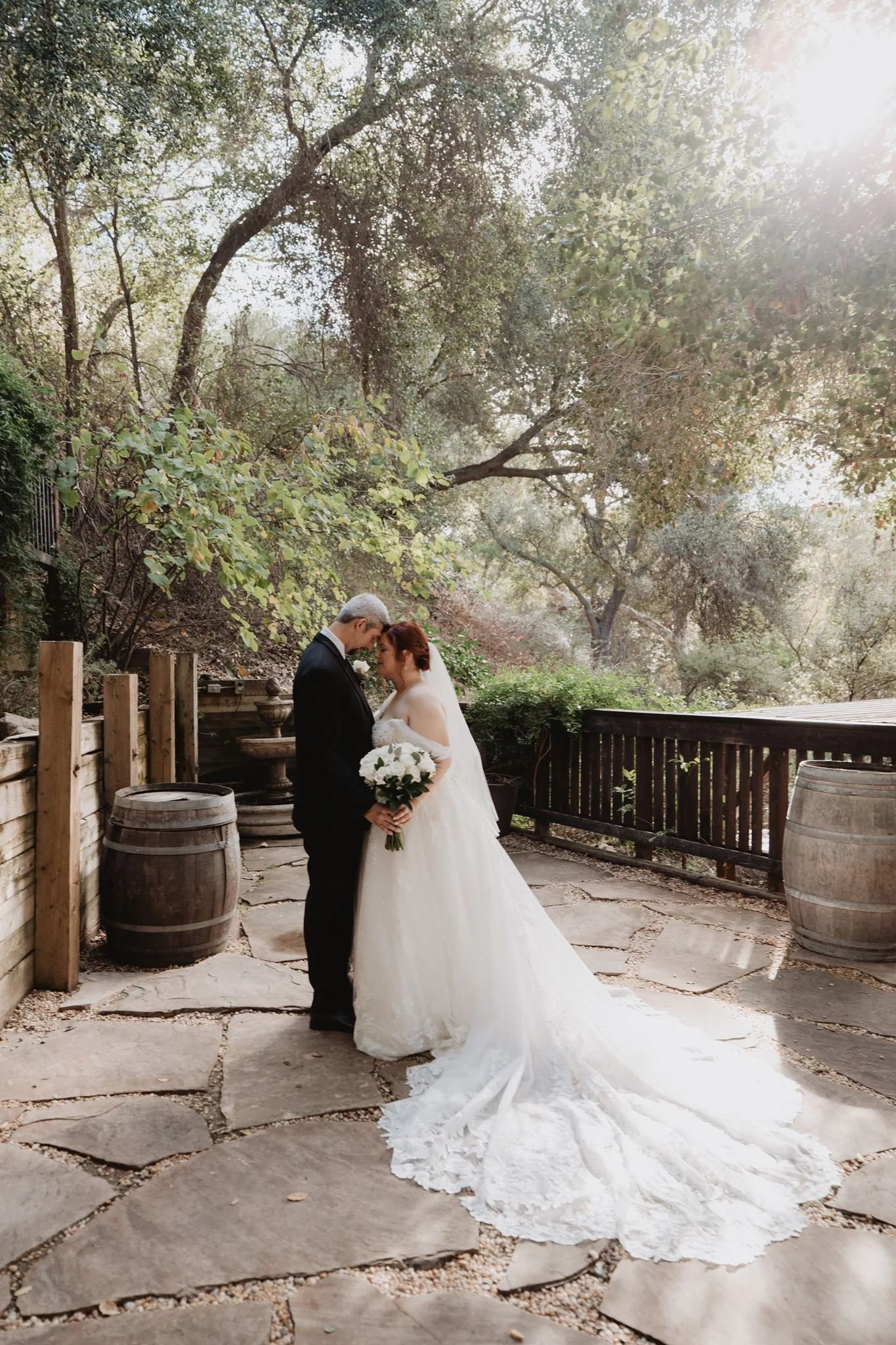 Couple on the flagstone path between wine barrels, shaded by oaks at The 1909 in Topanga