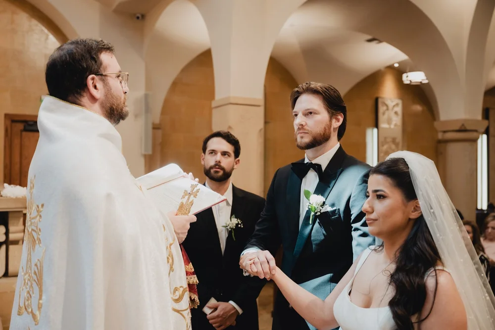 Bride and groom holding hands before the priest during an Armenian church ceremony