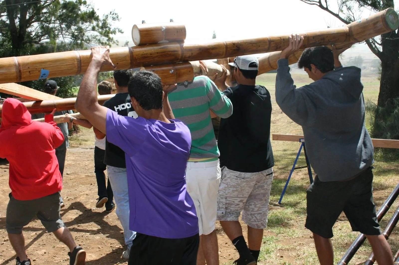 Six HPA students lifting a massive bamboo beam overhead together