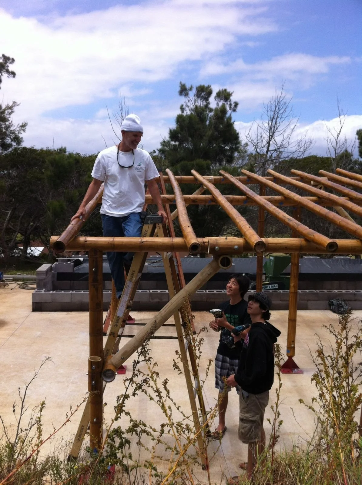 Bobby on ladder above students, laughing together mid-build