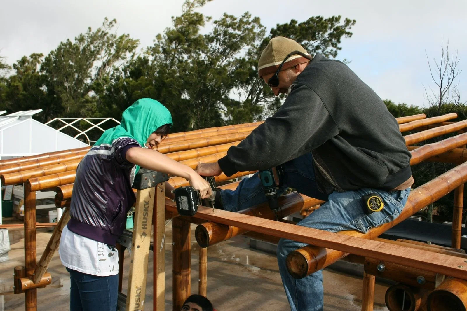 Bobby and student drilling side by side on the roof frame
