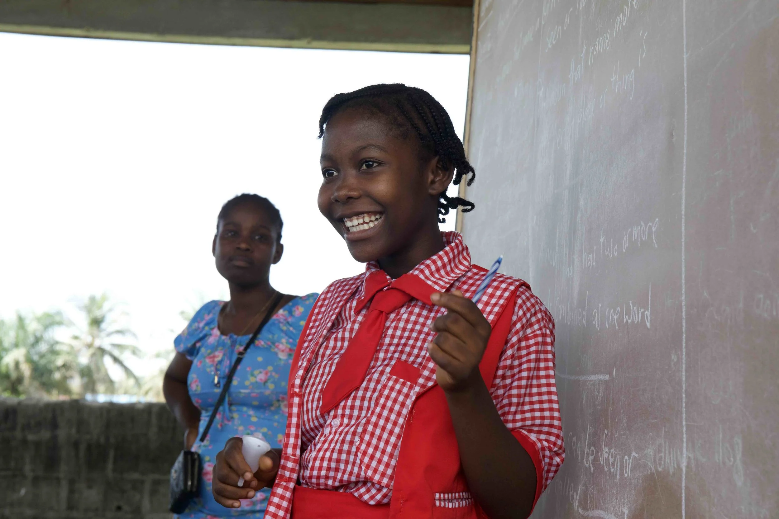 A girl smiling in front of a blackboard after a menstrual health education session