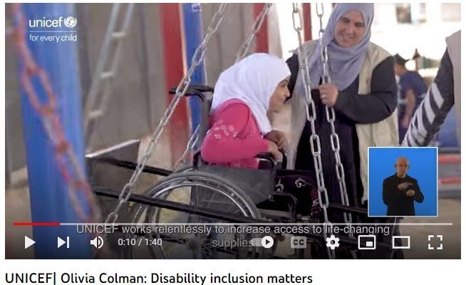 Screen shot from UNICEF's Olivia Coleman film.  Image of a young girl in a wheelchair smiling in an adapted swing.