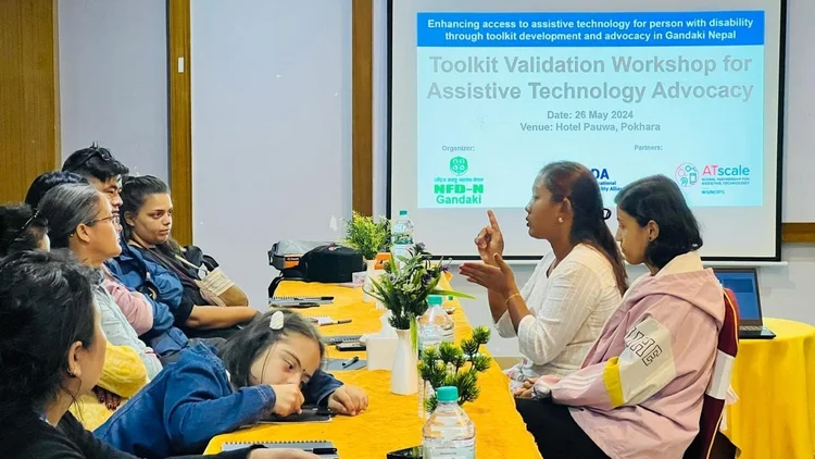 A photo of seven people listening to two people, using sign language, with one of the participant is using Braille. 