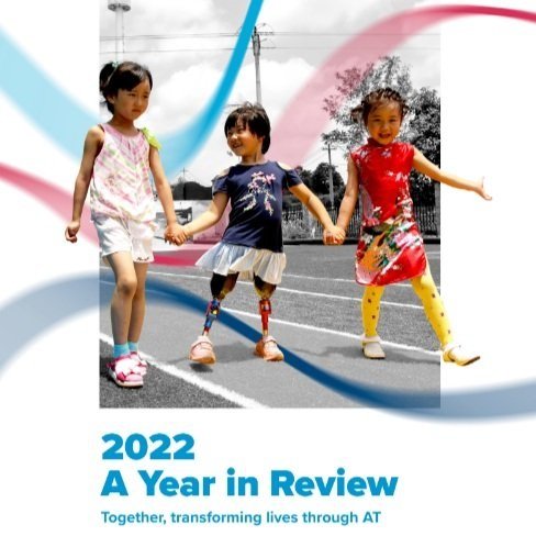 The front cover of the ATscale 2022 Year in Review shows three young Chinese girls holding hands and smiling.  The middle child has two prosthetic legs.  Text reads 2022 A Year in Review, Together, transforming lives through AT
