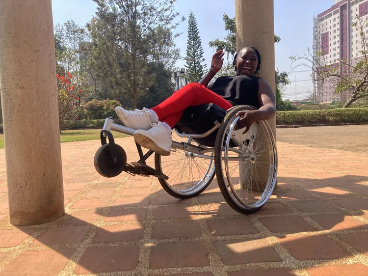 A photo of a women sitting on a wheel chair that is made in Kenya 