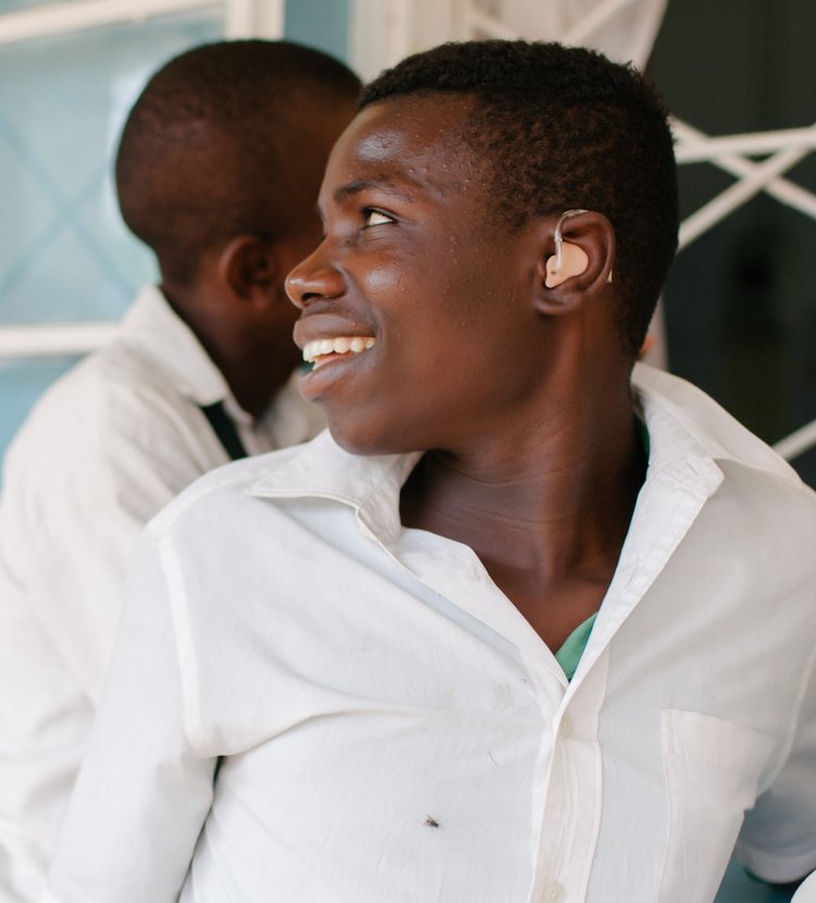 Young man in Zambia recently fitted for a hearing aid is smiling