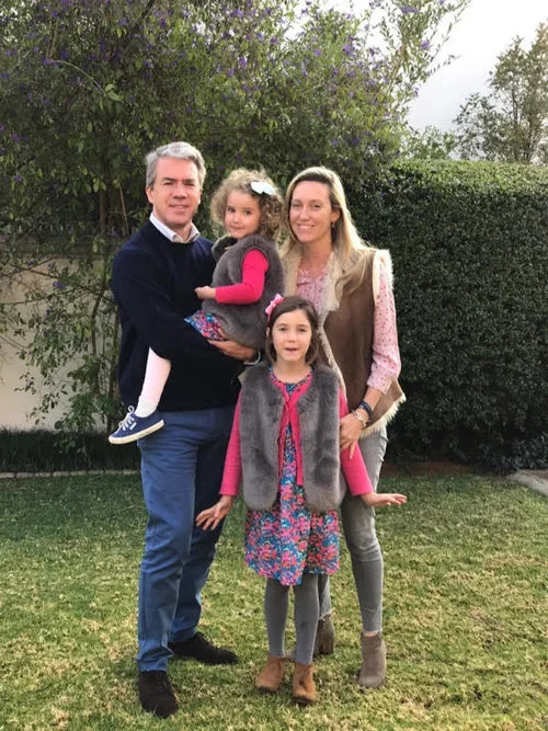 A client family in their garden under a jacaranda tree