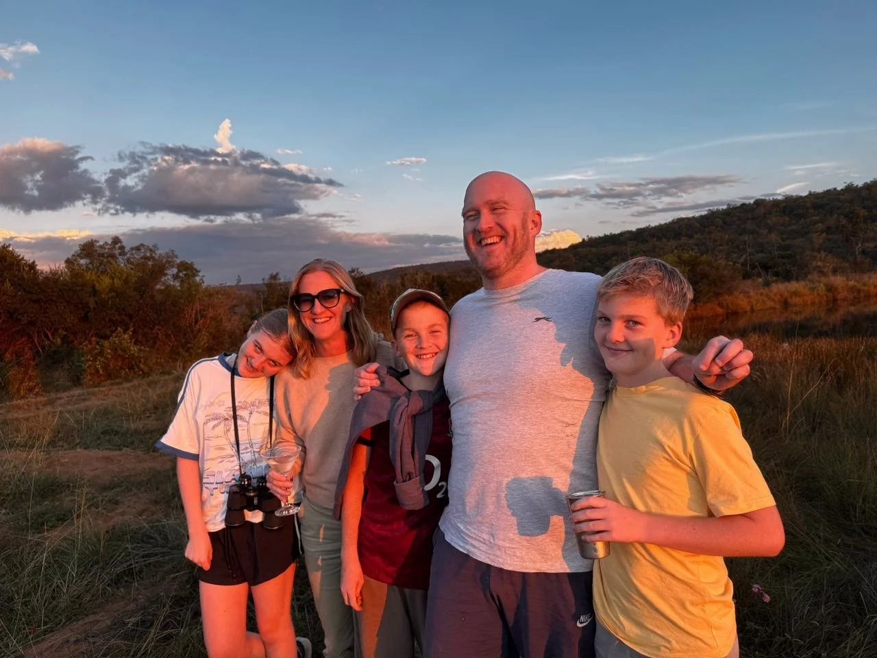 A smiling family of five together outdoors at sunset in the South African bushveld
