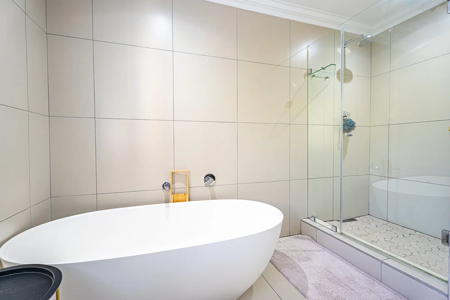 Bathroom with a freestanding oval bath and a walk-in shower behind glass