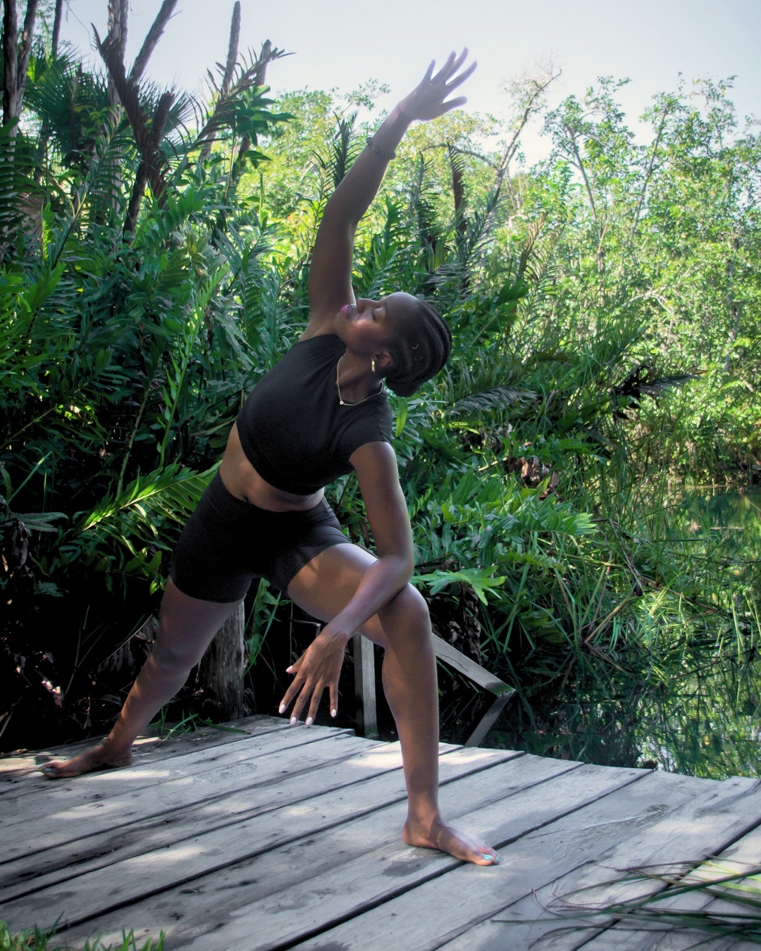 Biola practicing a backbend on a wooden dock surrounded by jungle