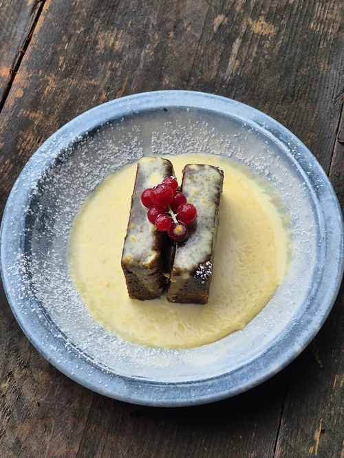 A sponge pudding with custard and raspberries