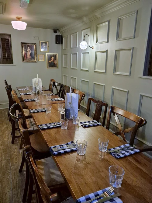 The private dining room laid for a group, with panelled walls and portraits