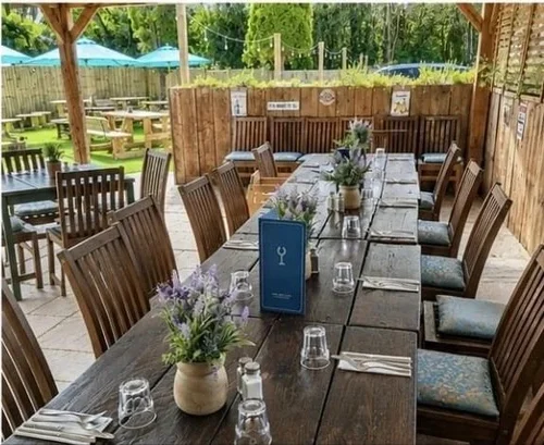 Tables laid along the covered terrace, looking out to the garden umbrellas