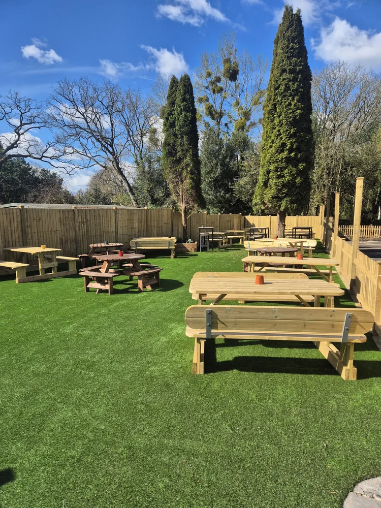 Picnic benches and round tables on the lawn in the pub garden