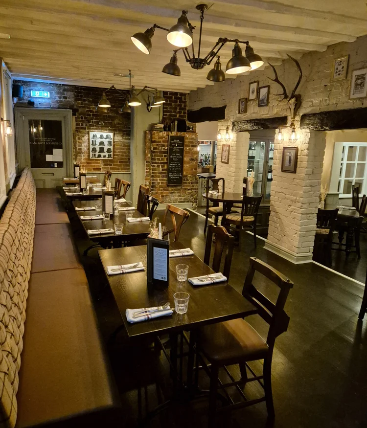 The dining room in the evening, with its long banquette and tables laid for dinner