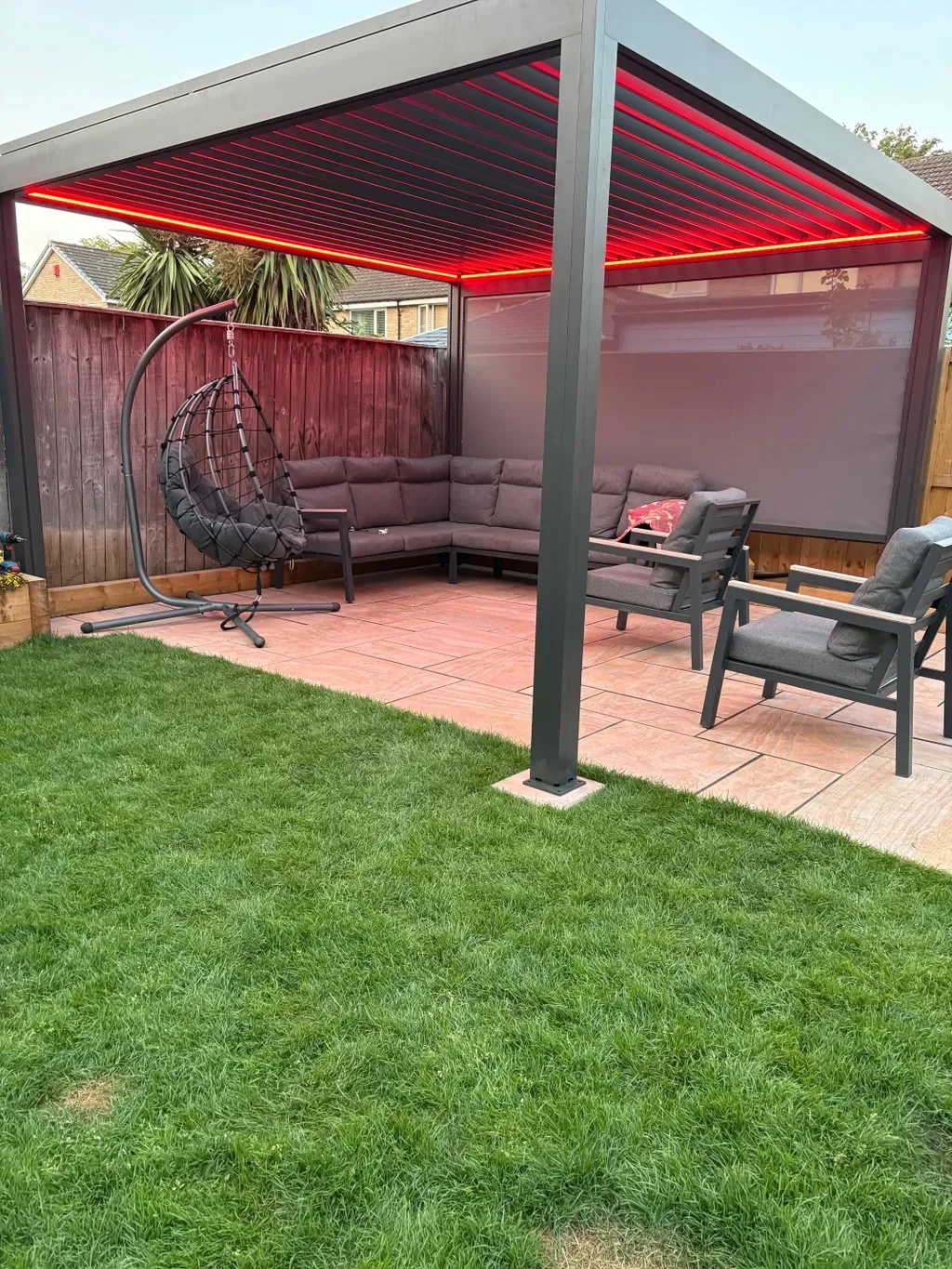 Charcoal louver pergola with red LED lighting and drop-down screen