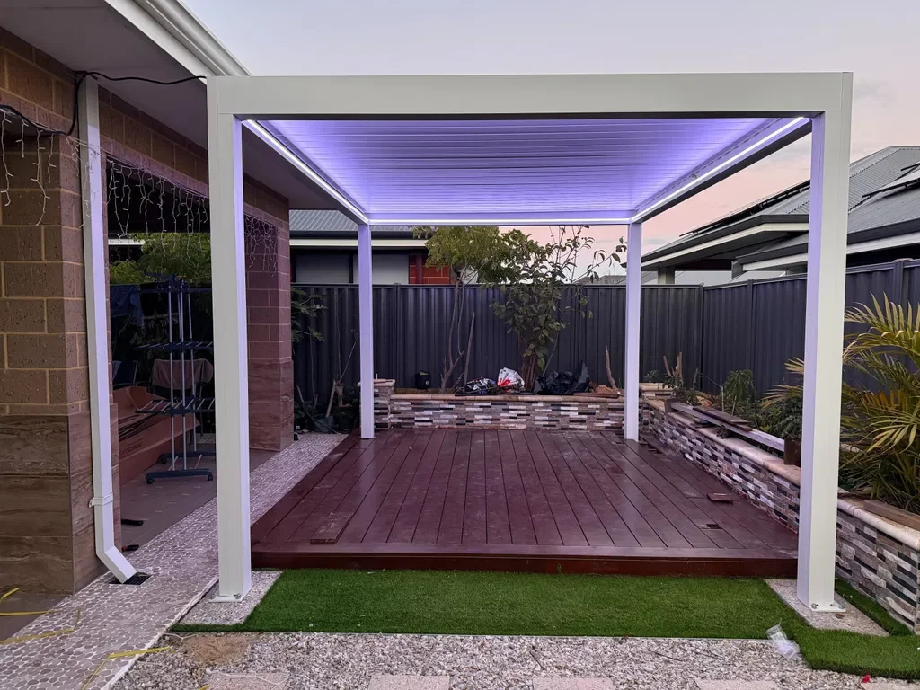 White louver pergola with colour LED lighting over a deck