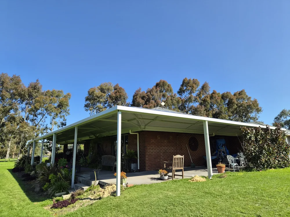 Hip roof patio running along the side of a brick home