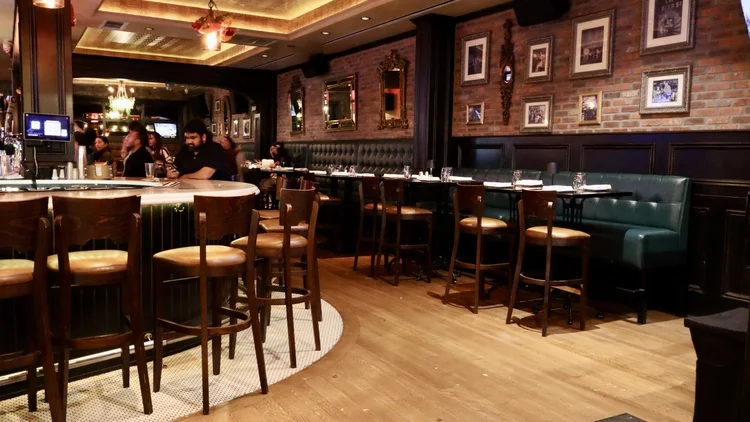 Brick wall, gilt mirrors and green banquettes in the dining room