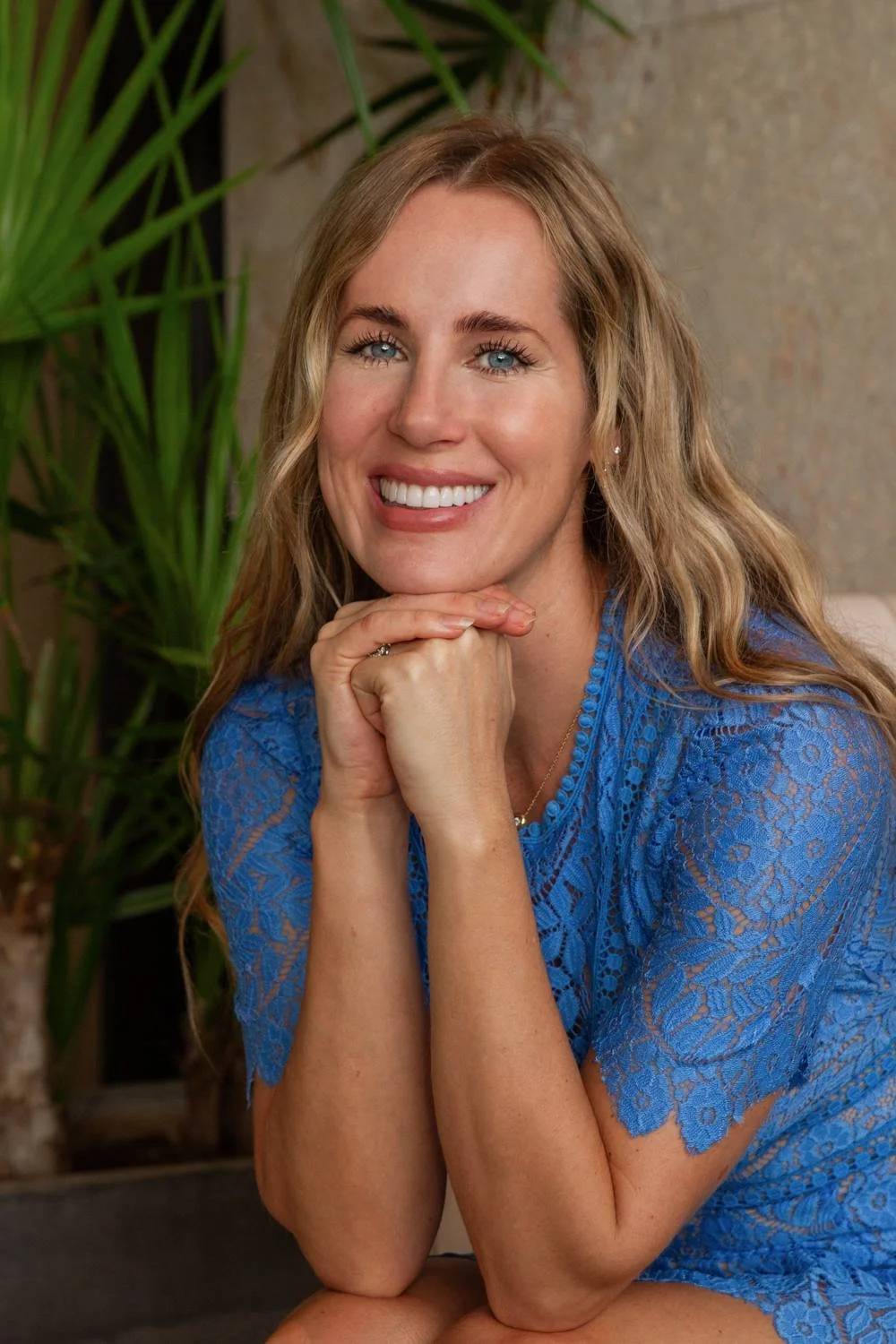 Megan Bruneau smiling, chin resting on her hands, in a blue lace dress