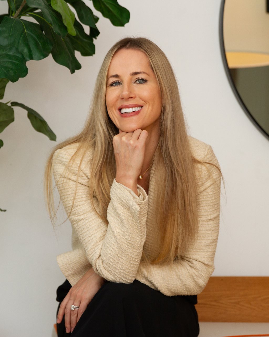 Megan Bruneau in a cream sweater, seated beside a fiddle-leaf fig