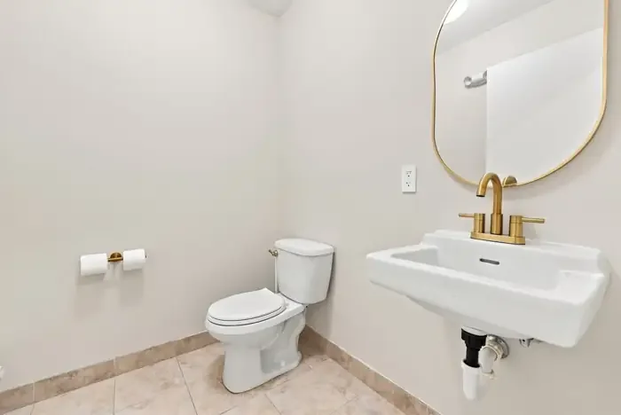 Restroom with brass fixtures and an arched mirror