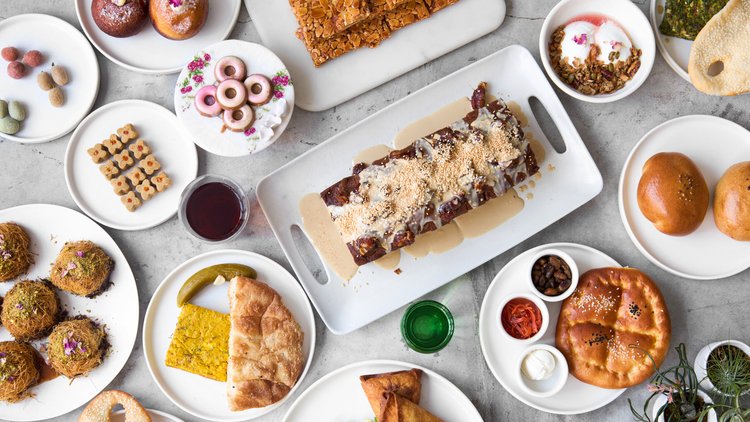 An assortment of savory and sweet items served in Sofreh Café in plates on a table, pictured from above