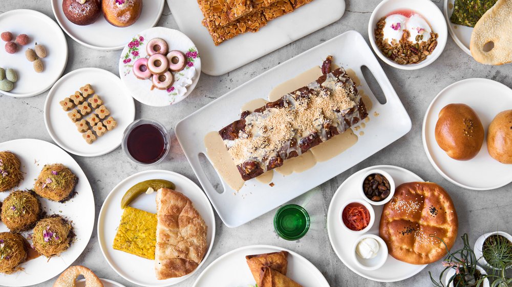 An assortment of savory and sweet items served in Sofreh Café in plates on a table, pictured from above