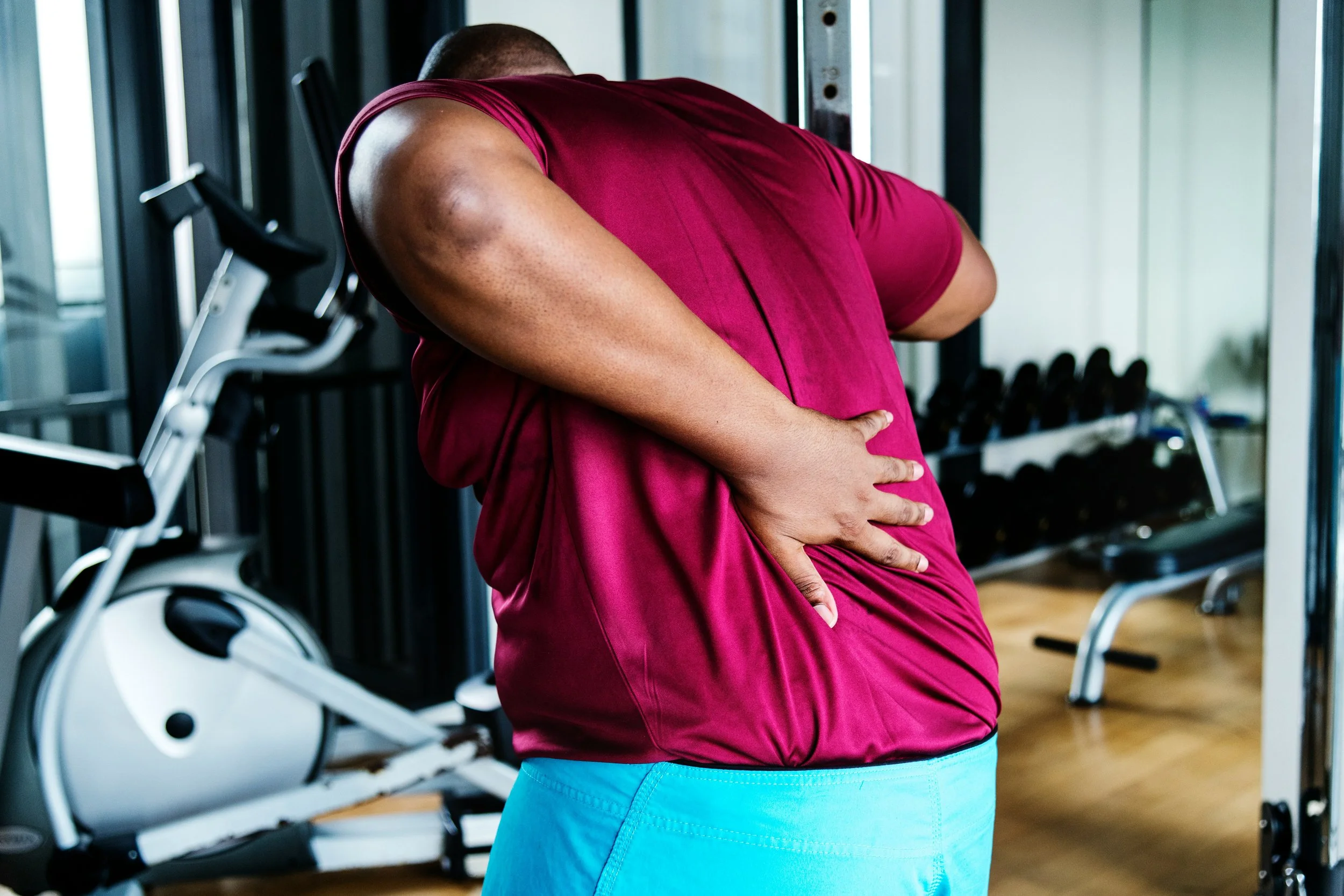 Gym member pausing during a workout holding shoulder in discomfort