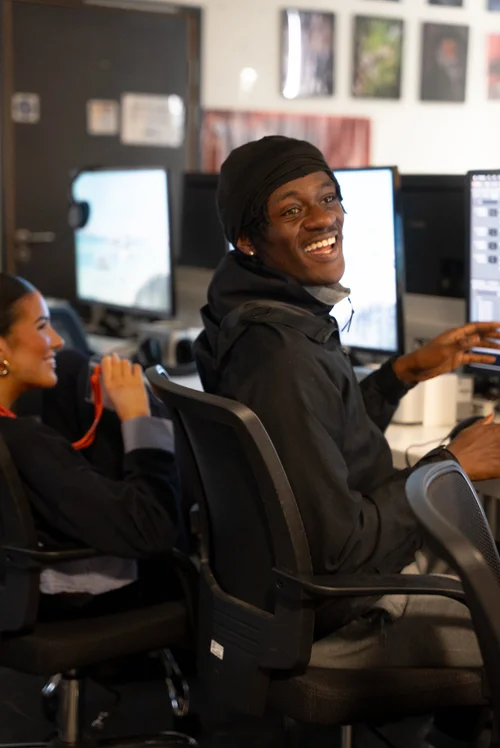 Smiling ELAM student turning from his computer in a classroom