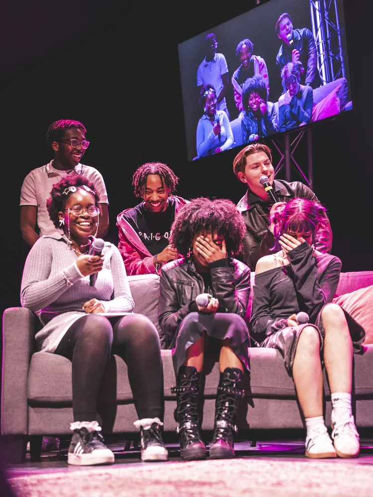 ELAM students laughing on stage during a panel, holding microphones