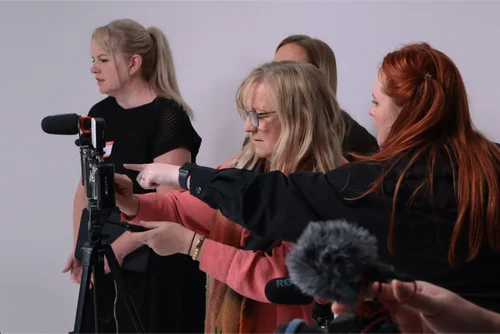 Teachers gathered around a camera during a filmmaking workshop
