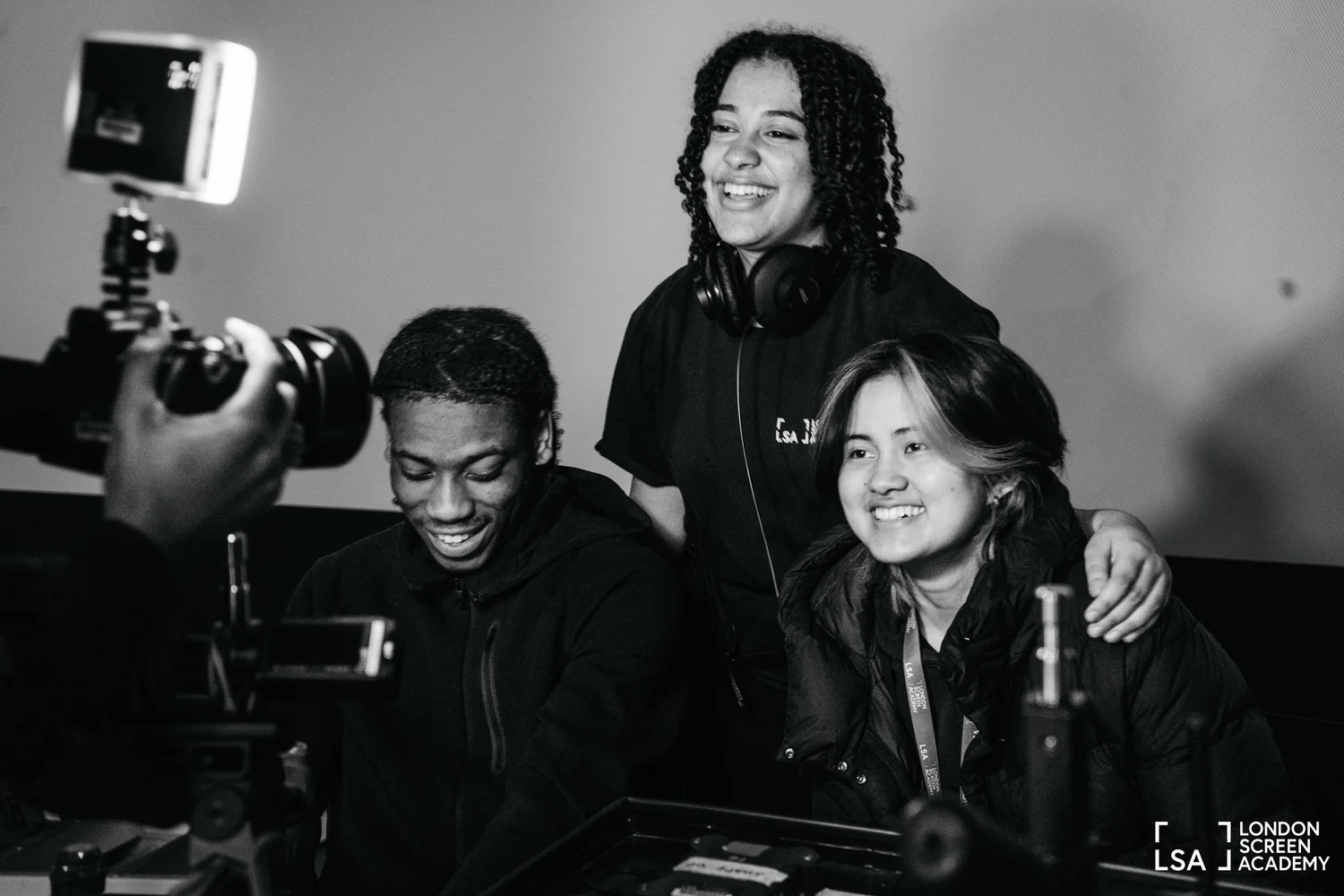 LSA students laughing together around a camera on a shoot