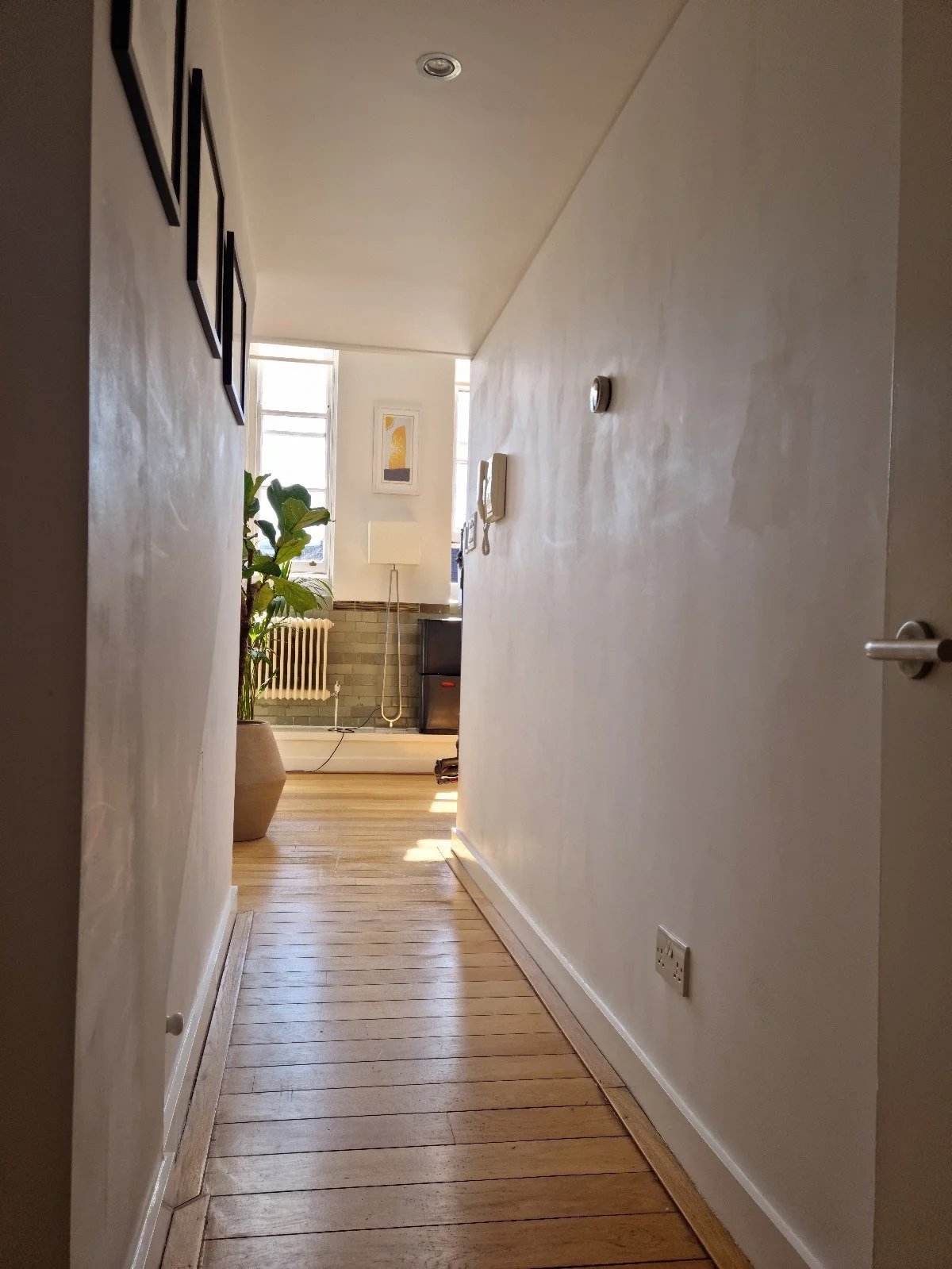 Before photo — dark narrow hallway in a Grade II listed school conversion duplex London, with worn straight-laid floorboards, hinged doors and no natural light, prior to Studio Akiva's renovation