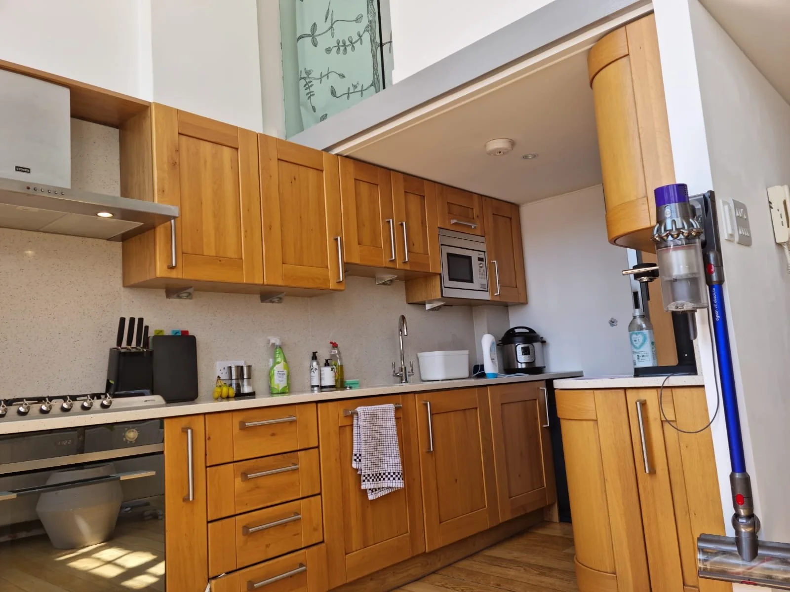 Before photo — double-height kitchen window wall in a Grade II listed school conversion duplex London, showing original sash windows and glazed dado tiles completely ignored by dated pine shaker cabinetry and chrome fittings, prior to Studio Akiva's redesign