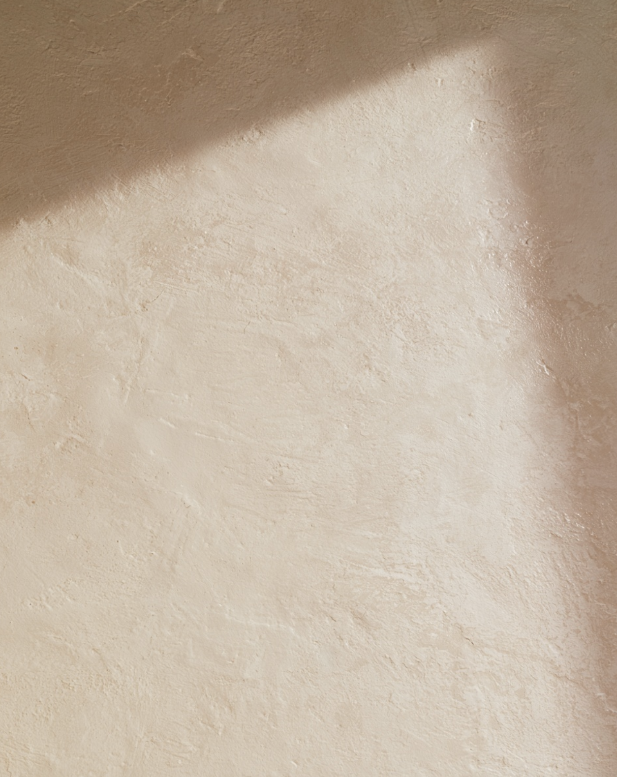 Close-up of a limewashed wall surface showing soft cloudy texture and tonal variation in warm beige tones