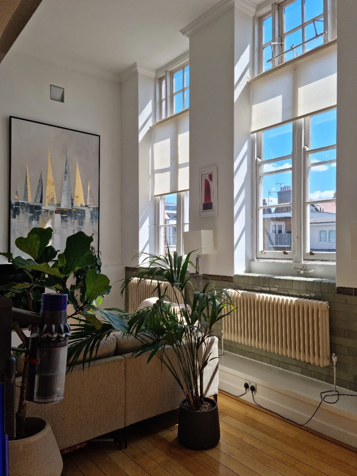 Before photo — living room of a Grade II listed school conversion duplex London, showing plain white walls, basic shelf unit with TV, cream column radiators and original glazed dado tiles completely unaddressed, prior to Studio Akiva's Japandi renovation