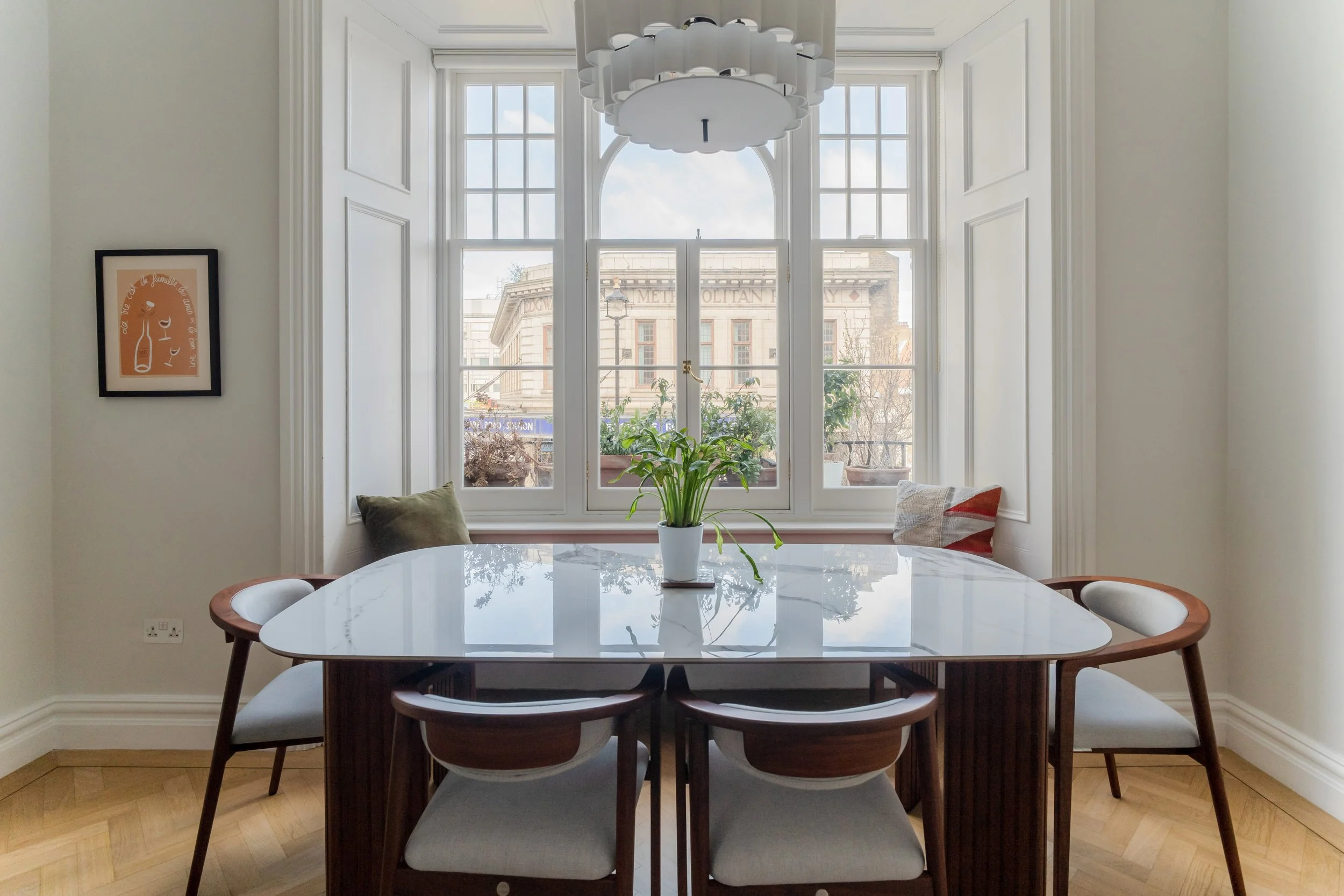 Bright dining area with marble dining table, statement pendant light, and large arched sash windows.