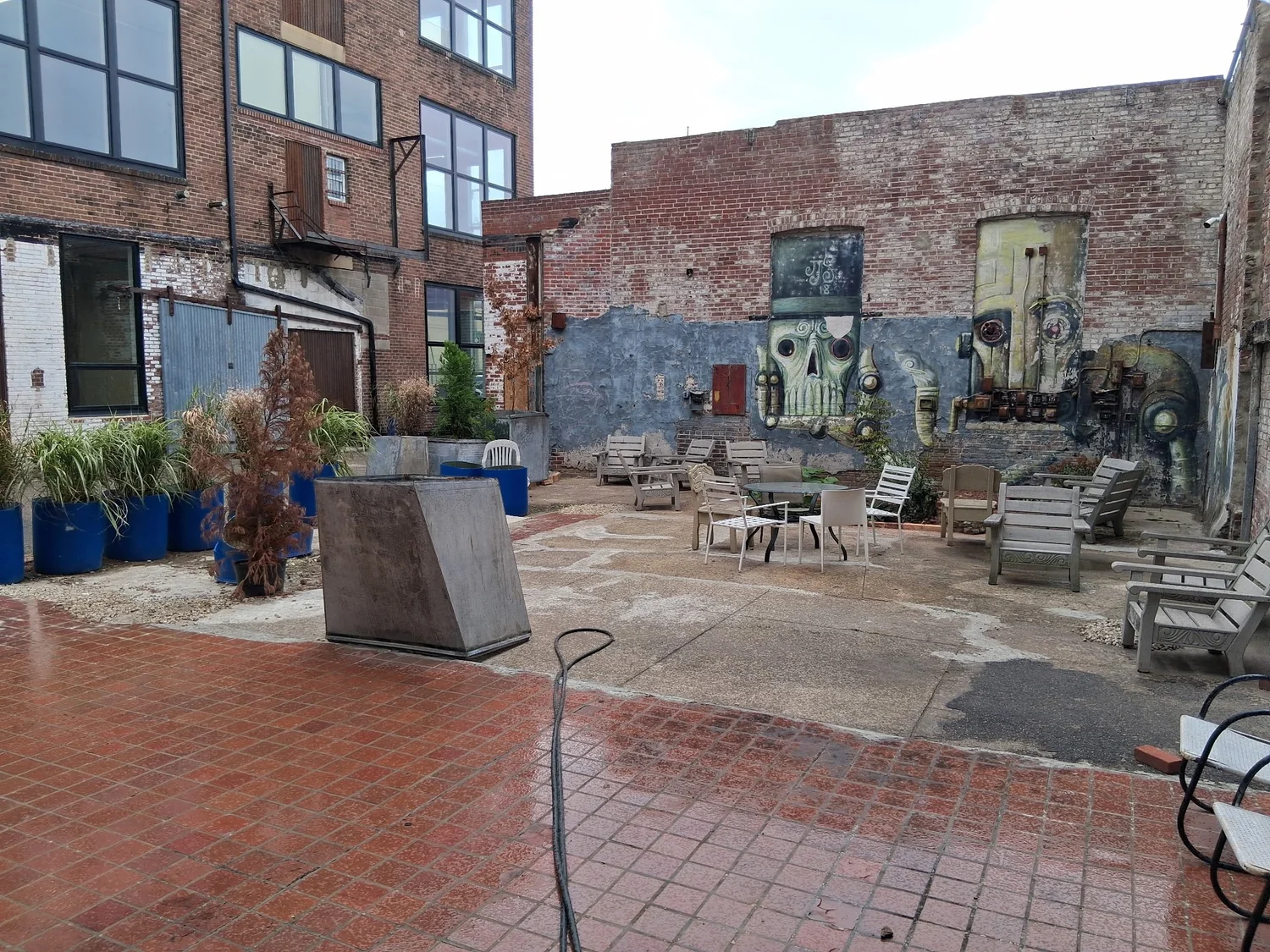 The private courtyard at D Street Studios, Philadelphia, with brick paving, painted murals on the mill walls and outdoor seating between the buildings