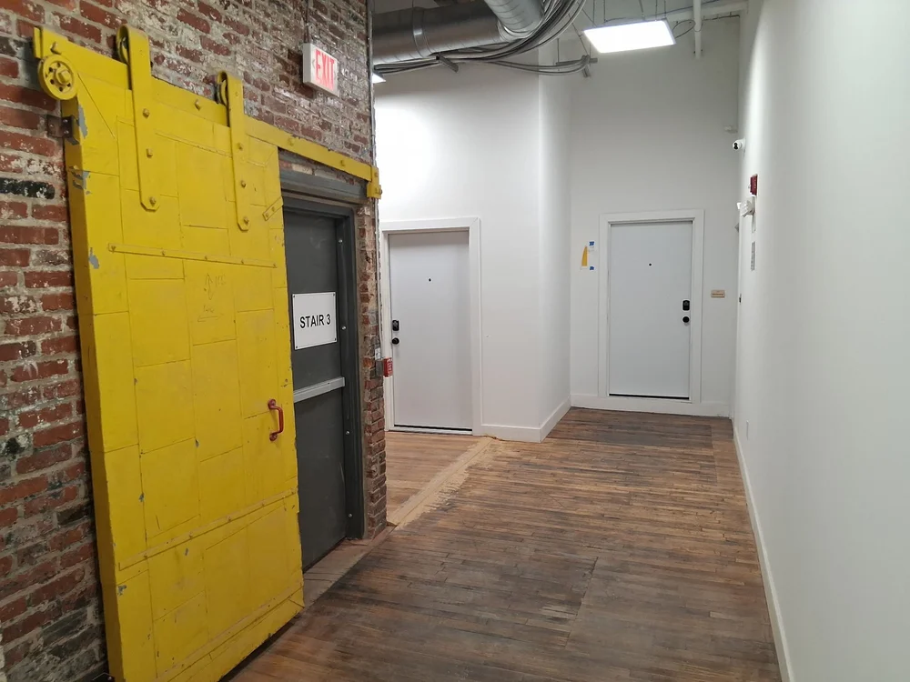 Yellow steel freight door and elevator access in a studio corridor at D Street Studios Philadelphia