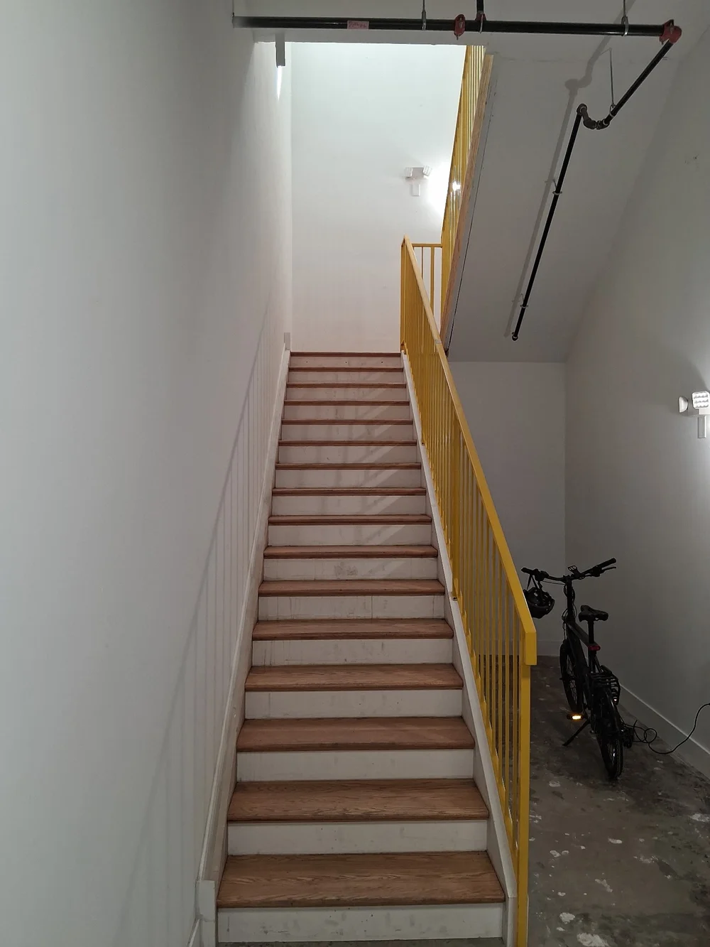 Interior stairwell with yellow painted handrail and bicycle parking at D Street Studios
