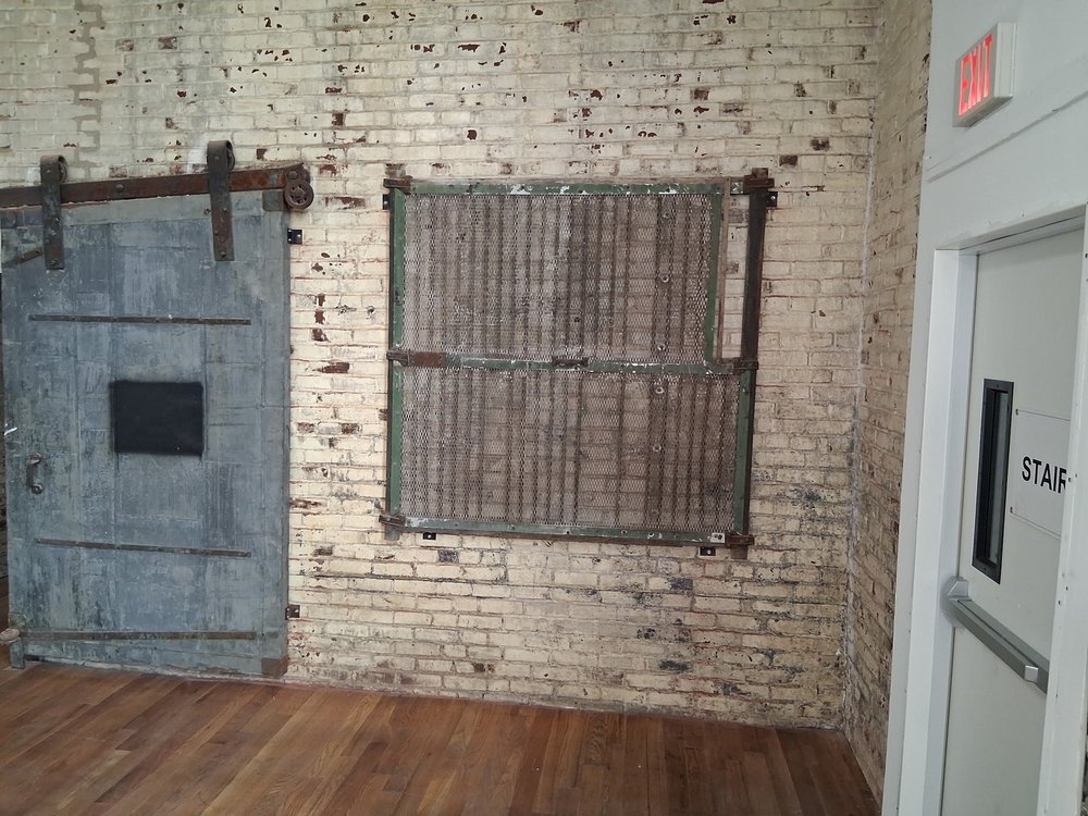 Original 1888 steel fire door preserved on an exposed brick wall inside D Street Studios, Philadelphia