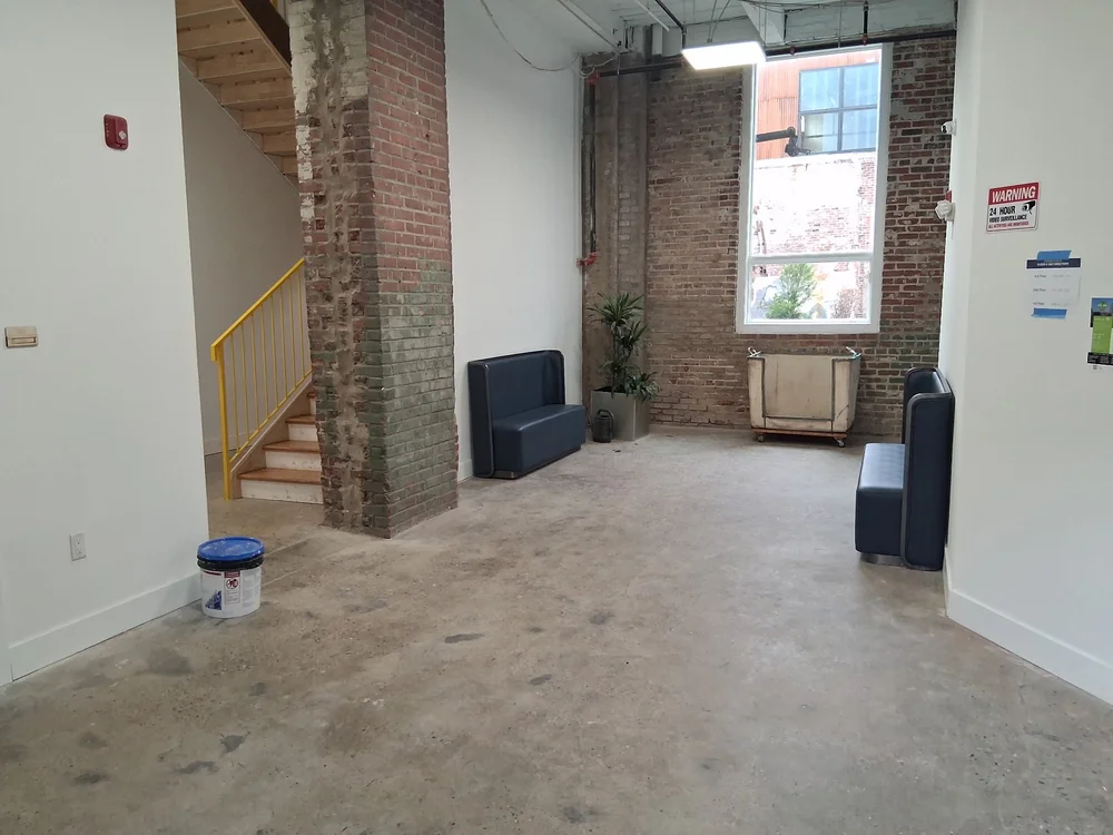 Building entrance lobby with polished concrete floor, stairs and tall windows at D Street Studios Philadelphia
