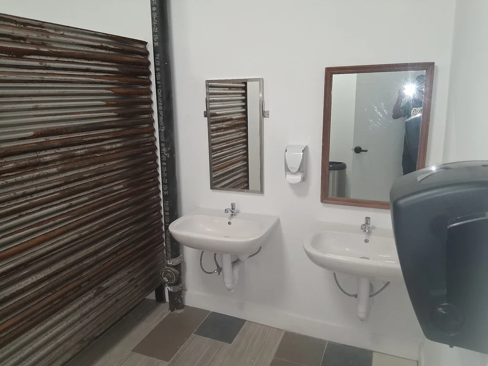 Renovated shared restroom with new sinks, mirrors and corrugated metal detailing at D Street Studios