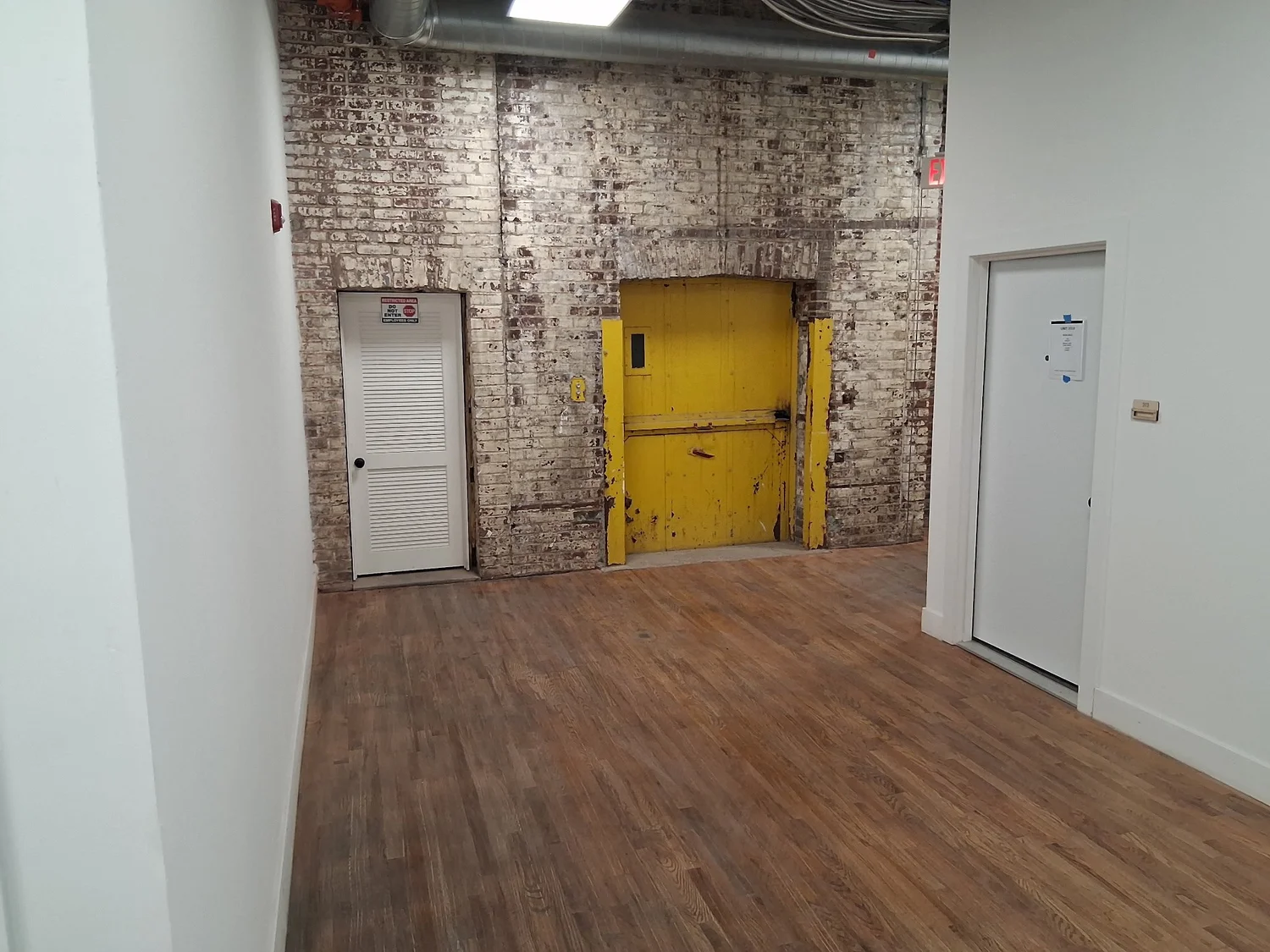 Restored mill interior with exposed brick, wood floors and a yellow steel freight door at D Street Studios, Philadelphia